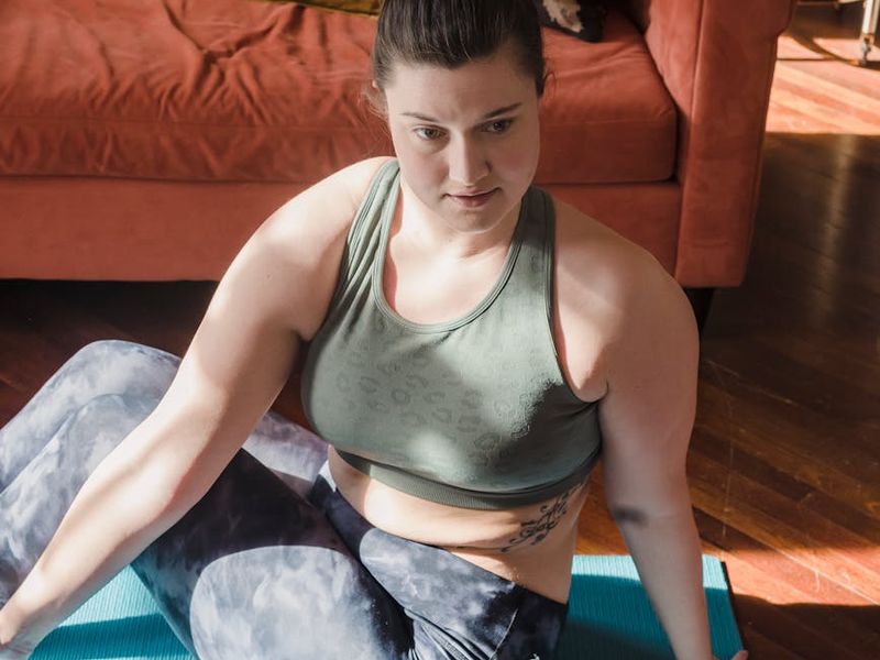 Person in a deep stretch yoga pose in a sunlit room.