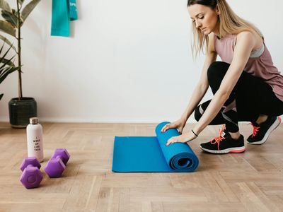 Rolled up yoga mat and a water bottle on a wooden floor.